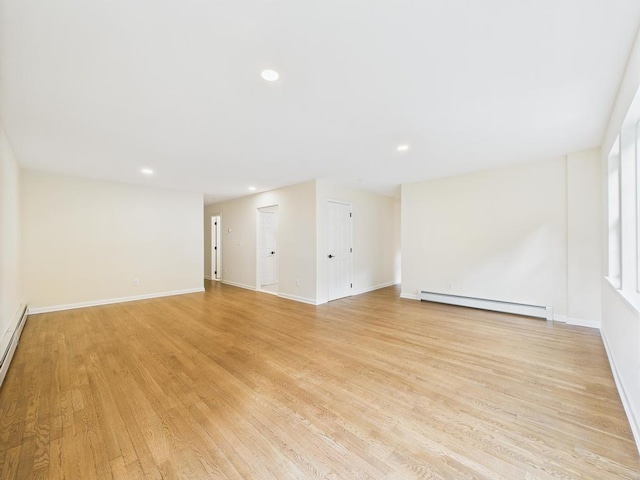 empty room with a baseboard heating unit, light wood-style floors, recessed lighting, and baseboards