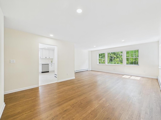 unfurnished living room featuring a baseboard heating unit, light wood-type flooring, baseboards, and recessed lighting