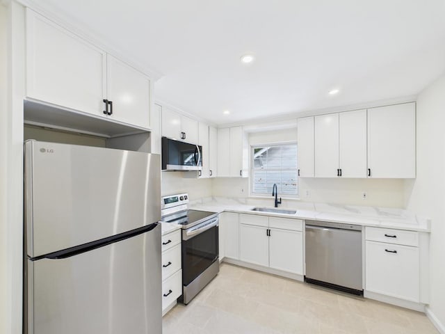 kitchen with appliances with stainless steel finishes, a sink, white cabinetry, light stone countertops, and recessed lighting