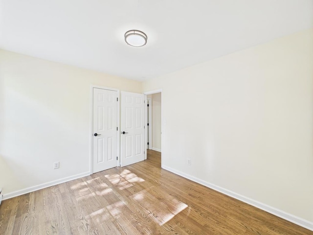 unfurnished bedroom with baseboards, wood finished floors, and a closet