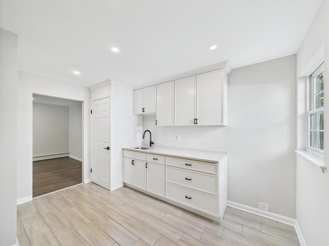 kitchen featuring a sink, light countertops, baseboards, light wood-style flooring, and recessed lighting