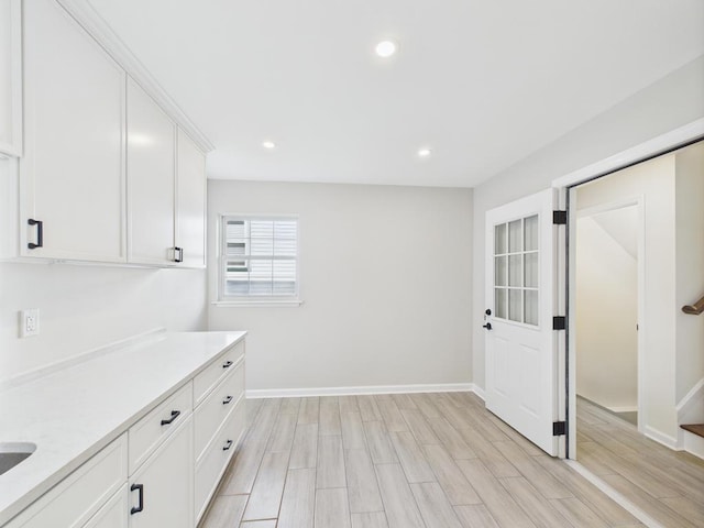 kitchen featuring light countertops, white cabinetry, light wood-style floors, recessed lighting, and baseboards