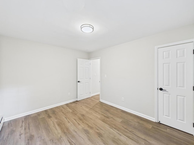 spare room with wood finished floors, baseboards, and baseboard heating