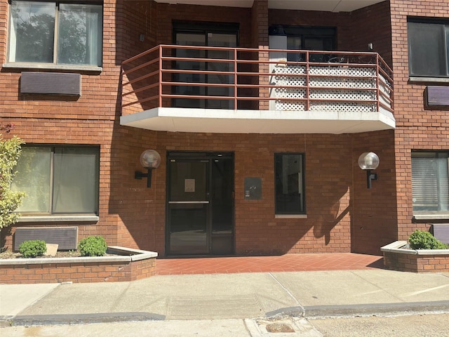 doorway to property featuring brick siding and a balcony
