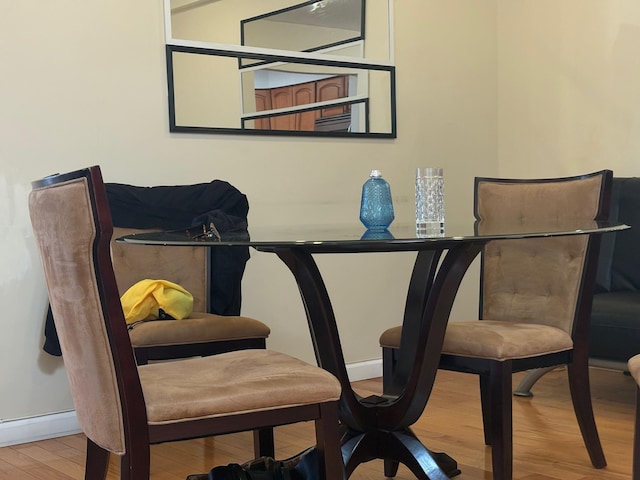 dining space featuring wood finished floors, baseboards, and a baseboard heating unit