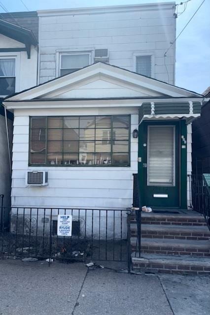 view of front facade featuring a fenced front yard and a wall mounted AC