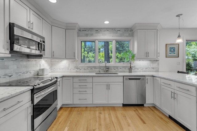 10 Bay Dr W, Huntington Bay, NY 11743 - kitchen with appliances with stainless steel finishes, a sink, backsplash, a peninsula, and light wood-style floors