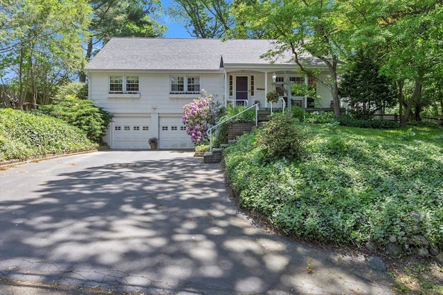 10 Bay Dr W, Huntington Bay, NY 11743 - view of front of property featuring concrete driveway, a garage, covered porch, a shingled roof, and stairway