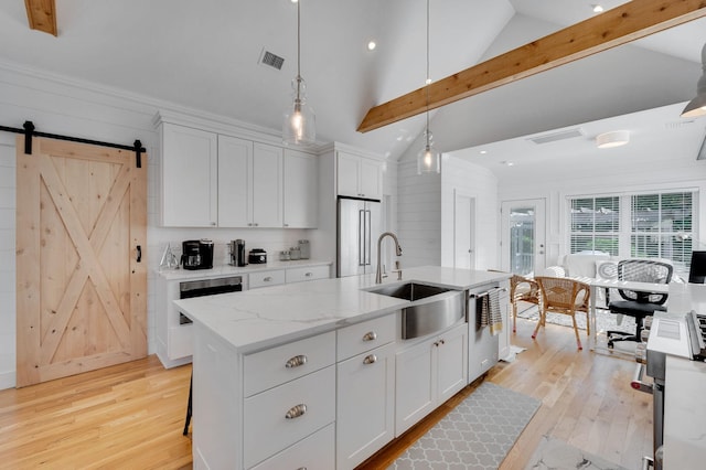 kitchen featuring appliances with stainless steel finishes, a sink, light wood-style floors, white cabinetry, and recessed lighting