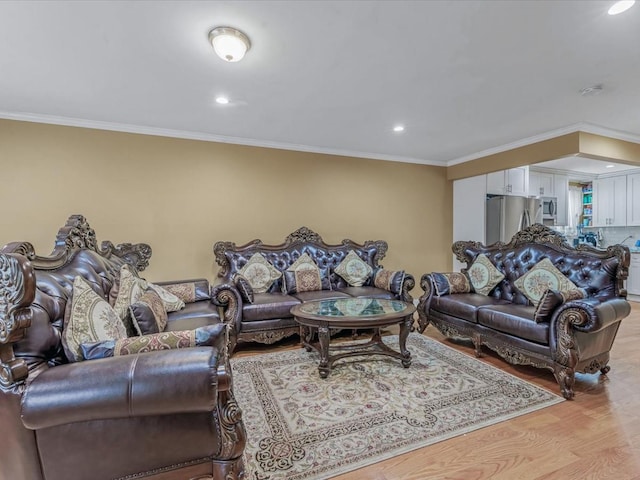 living area with ornamental molding, light wood-style flooring, and recessed lighting