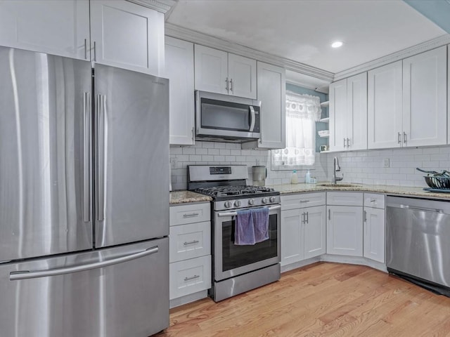 kitchen featuring appliances with stainless steel finishes, a sink, light wood-type flooring, decorative backsplash, and recessed lighting