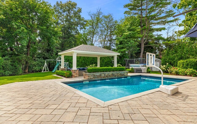 15 Wagamon Dr, Woodbury, NY 11797 - outdoor pool featuring a gazebo, a patio, a playground, view of scattered trees, and a lawn