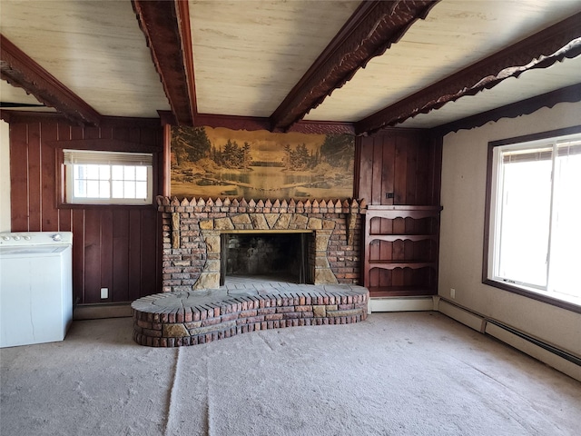 living room featuring washer / dryer, carpet flooring, beam ceiling, a fireplace with raised hearth, and wooden walls