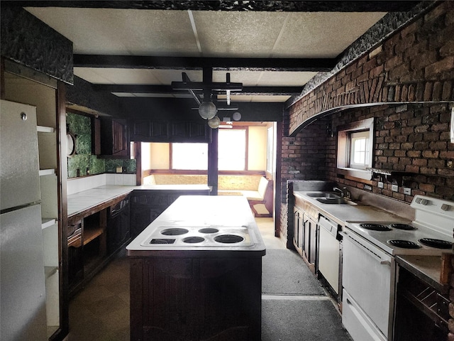 kitchen with white appliances, a sink, a center island, and brick wall