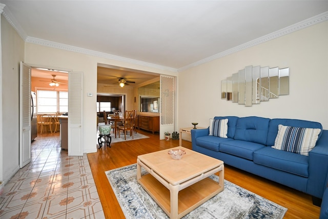 living area featuring crown molding, a ceiling fan, and light wood-style flooring
