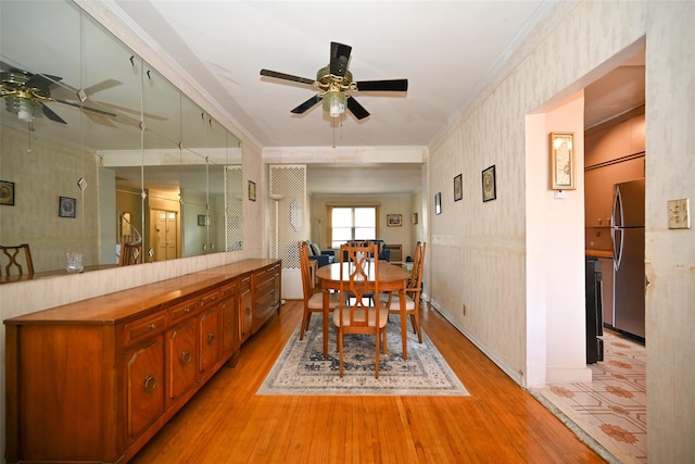 dining room featuring ceiling fan, ornamental molding, light wood-style flooring, and wallpapered walls
