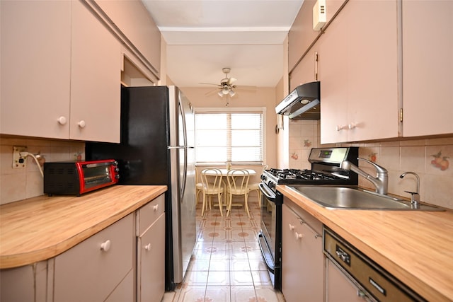kitchen featuring under cabinet range hood, butcher block countertops, stainless steel appliances, and a sink
