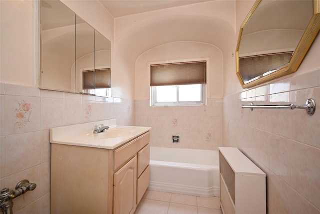 full bath with tile walls, tile patterned flooring, a tub, vanity, and a wainscoted wall