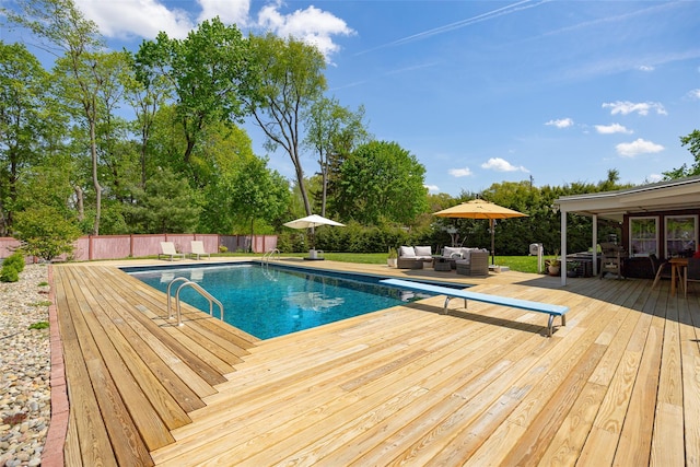 view of swimming pool with an outdoor hangout area, a deck, a fenced backyard, and a diving board