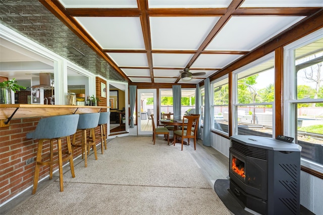 sunroom with a wood stove and wood finished floors