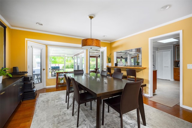 dining room with crown molding, wood finished floors, and baseboards