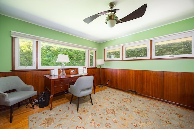 home office featuring a wainscoted wall, wood finished floors, ceiling fan, and wood walls