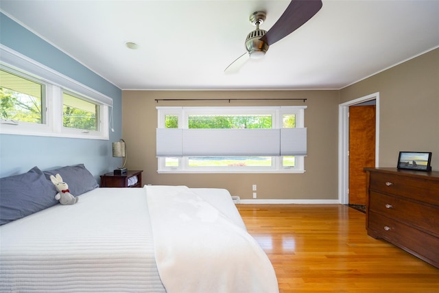 bedroom featuring light wood-type flooring, ceiling fan, baseboards, and ornamental molding