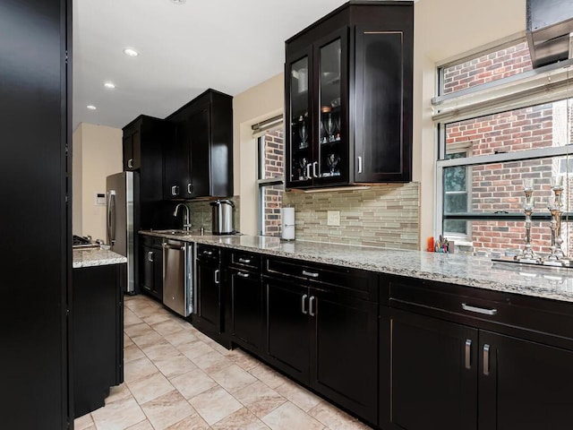 kitchen featuring stainless steel appliances, dark cabinets, decorative backsplash, and recessed lighting