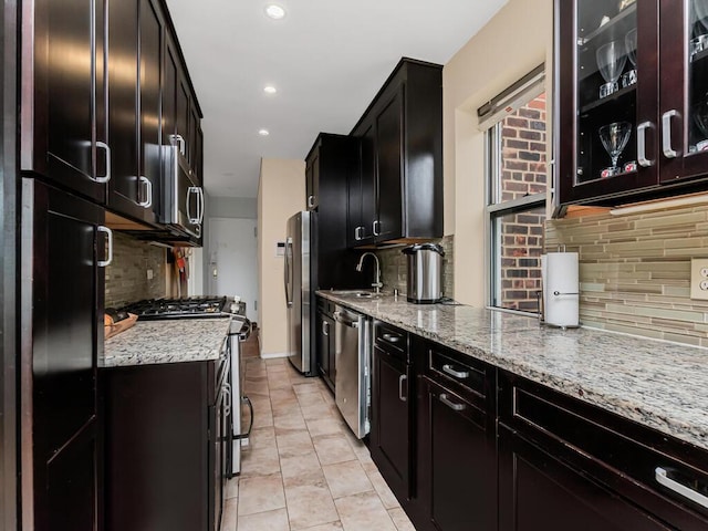 kitchen featuring stainless steel appliances, decorative backsplash, a sink, light stone countertops, and recessed lighting