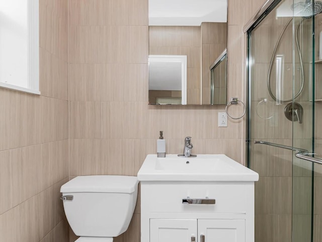 full bath featuring tile walls, a shower stall, vanity, and toilet