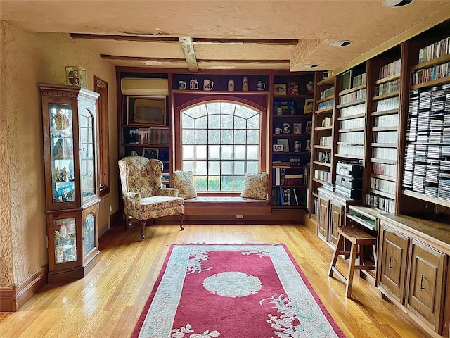 59 Sunset Rd, Bay Shore, NY 11706 - living area with light wood-style floors, an AC wall unit, beamed ceiling, built in features, and a textured wall