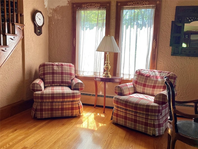 59 Sunset Rd, Bay Shore, NY 11706 - living area featuring a textured wall, a baseboard radiator, wood finished floors, and healthy amount of natural light
