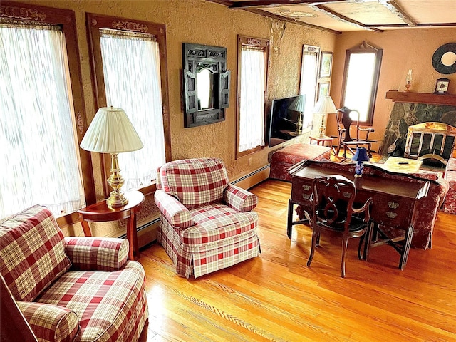 59 Sunset Rd, Bay Shore, NY 11706 - living area with a fireplace, baseboard heating, wood finished floors, a textured wall, and healthy amount of natural light