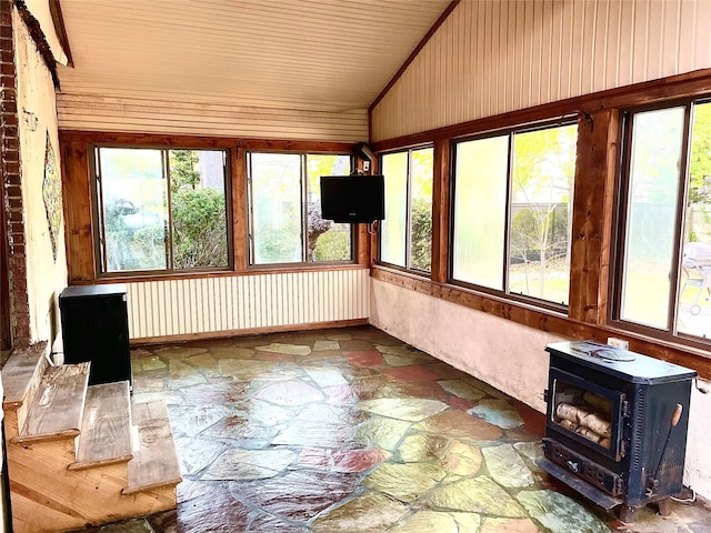 59 Sunset Rd, Bay Shore, NY 11706 - unfurnished sunroom featuring stone flooring, a wood stove, plenty of natural light, vaulted ceiling, and wood walls