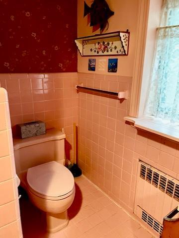 59 Sunset Rd, Bay Shore, NY 11706 - bathroom with radiator heating unit, tile walls, a wainscoted wall, and tile patterned floors
