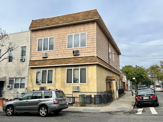 60-85 55th St, Maspeth, NY 11378 - view of side of property featuring roof with shingles, fence, cooling unit, and a wall mounted AC
