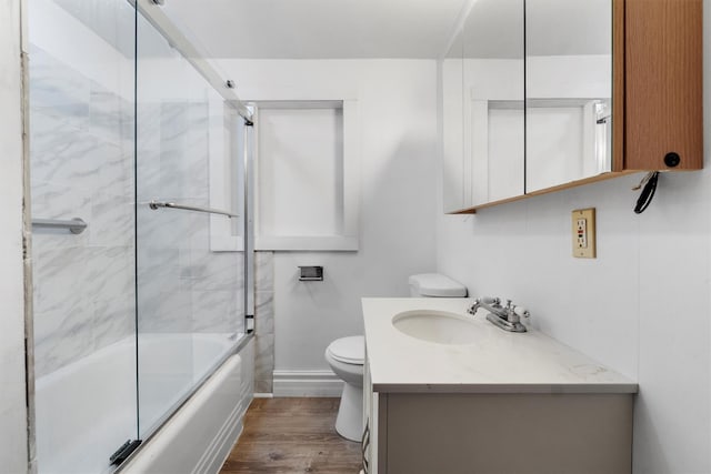 full bathroom featuring toilet, baseboards, wood finished floors, vanity, and enclosed tub / shower combo