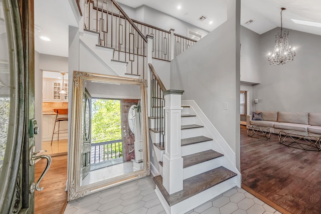 stairs featuring high vaulted ceiling, a chandelier, and wood finished floors