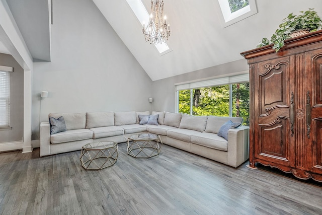 living room with a skylight, high vaulted ceiling, wood finished floors, a chandelier, and baseboards