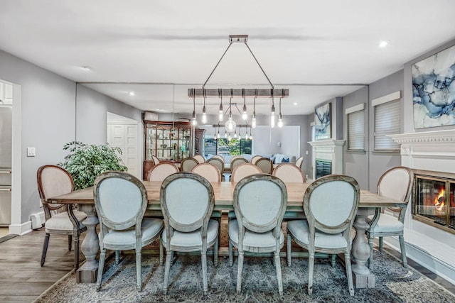dining room with a glass covered fireplace, wood finished floors, recessed lighting, and baseboards