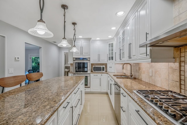 kitchen with a sink, range hood, appliances with stainless steel finishes, white cabinets, and light stone counters