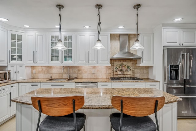 kitchen with stainless steel appliances, wall chimney exhaust hood, a sink, a kitchen breakfast bar, and white cabinets