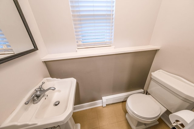 half bath featuring a baseboard heating unit, toilet, and healthy amount of natural light