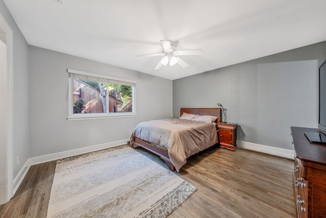 bedroom featuring baseboards, wood finished floors, and a ceiling fan