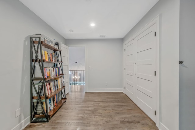 corridor featuring light wood-type flooring and baseboards