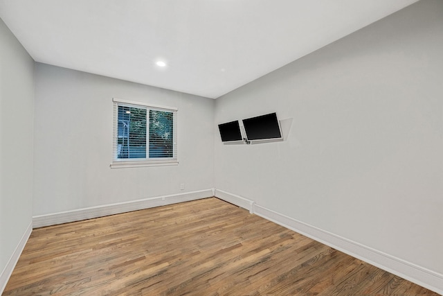 unfurnished room with wood finished floors, baseboards, and recessed lighting