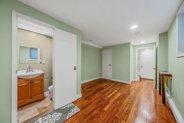 unfurnished living room with a sink, light wood finished floors, recessed lighting, and baseboards