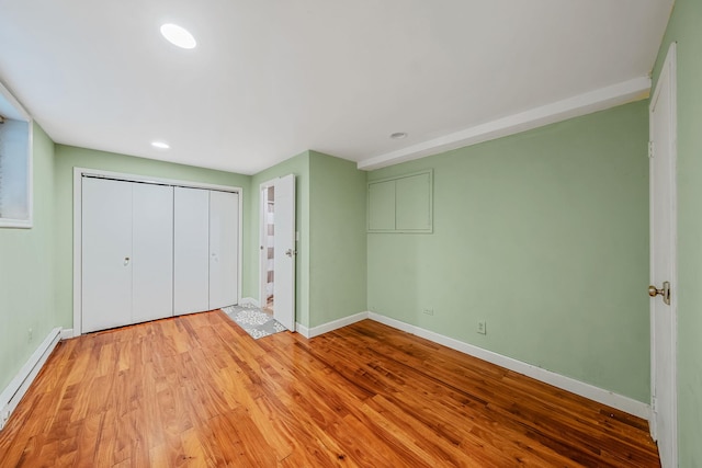 unfurnished bedroom with baseboards, a baseboard heating unit, wood finished floors, a closet, and recessed lighting