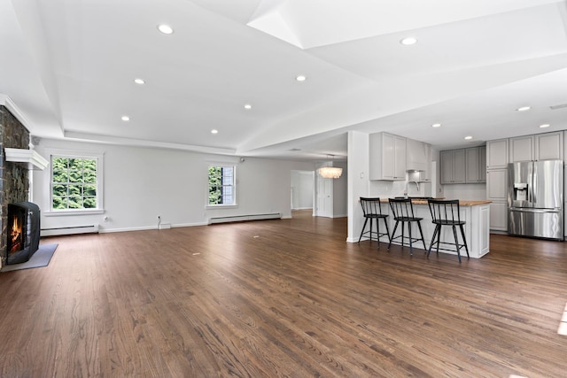 living room with baseboard heating, healthy amount of natural light, dark wood-style floors, recessed lighting, and lofted ceiling