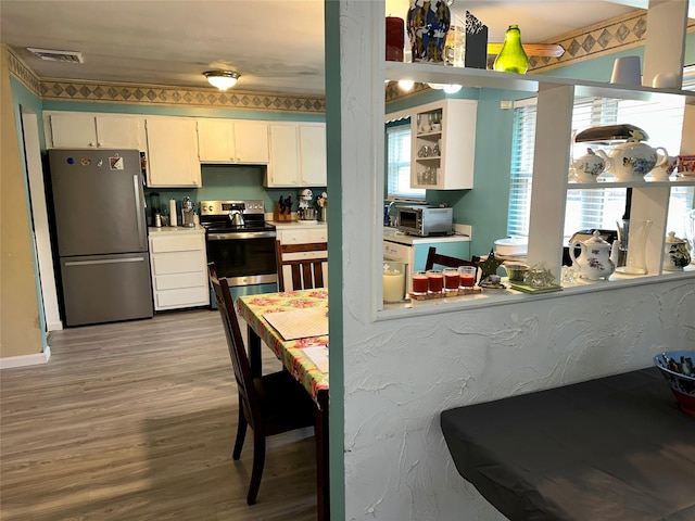 23 Hawkins Path, Coram, NY 11727 - kitchen with appliances with stainless steel finishes, wood finished floors, light countertops, white cabinets, and baseboards
